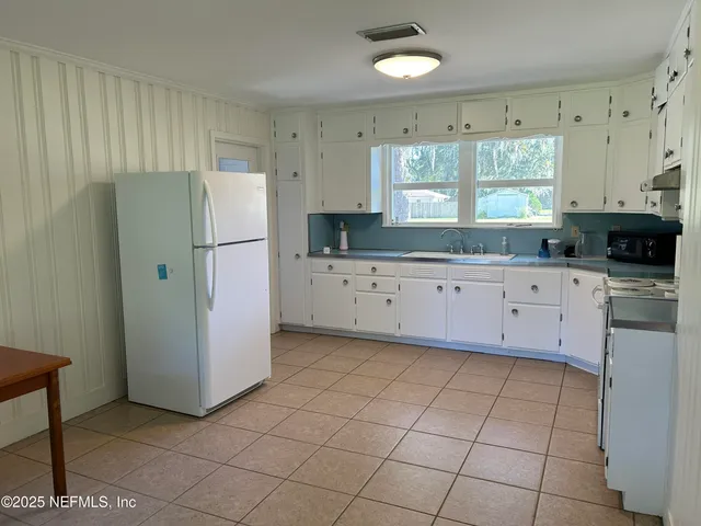 a kitchen with granite countertop white cabinets and refrigerator