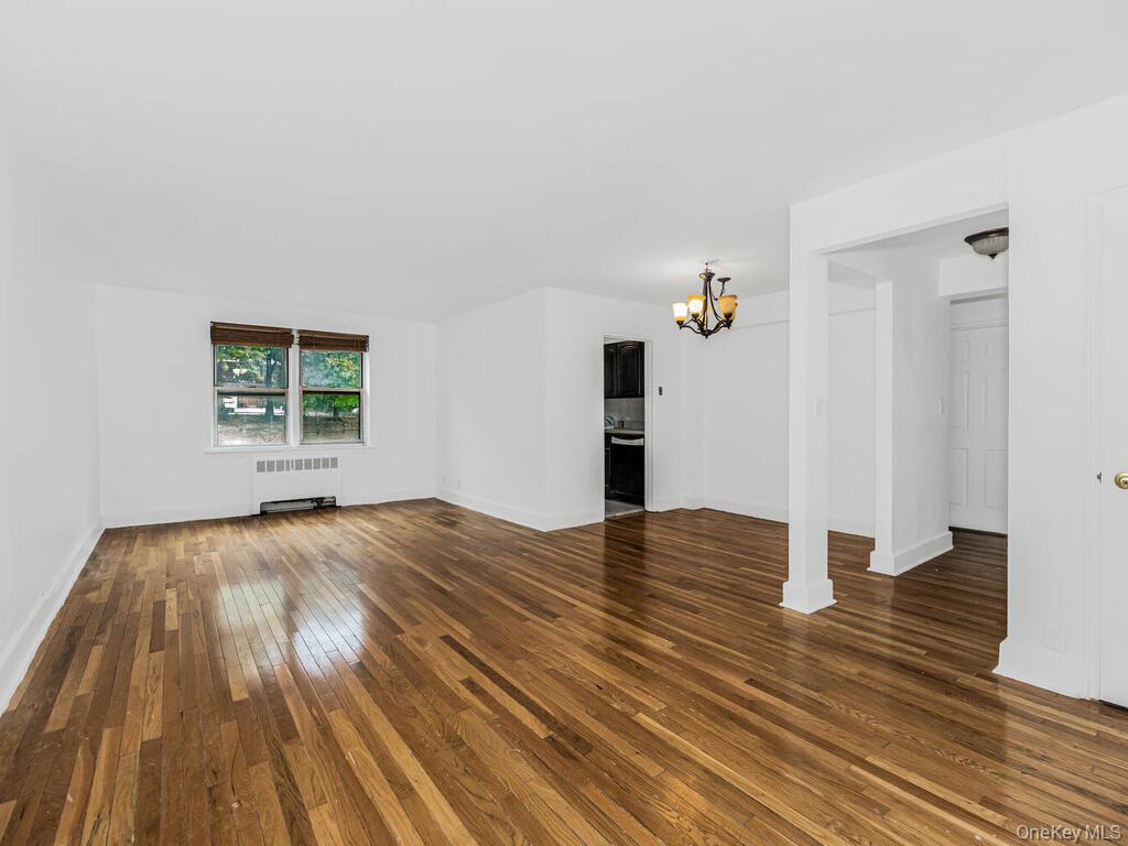 144 Ravine Avenue, Unit 2C Yonkers, NY 10701 - Photo 1 of 15 Unfurnished living room featuring radiator heating unit, a chandelier, and dark hardwood / wood-style flooring