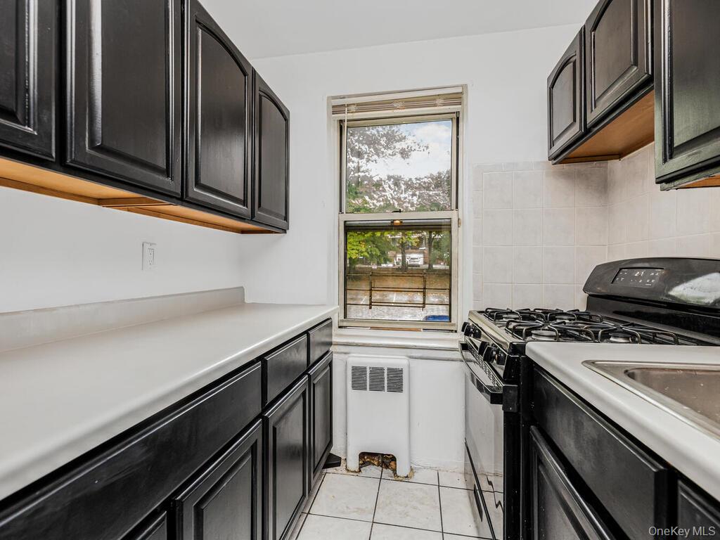 144 Ravine Avenue, Unit 2C Yonkers, NY 10701 - Photo 11 of 15 Kitchen with decorative backsplash, light tile patterned flooring, radiator, and black gas range