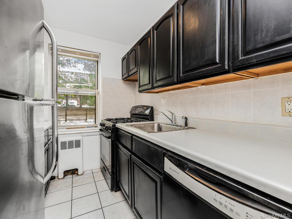 144 Ravine Avenue, Unit 2C Yonkers, NY 10701 - Photo 2 of 15 Kitchen with light tile patterned flooring, backsplash, radiator heating unit, stainless steel appliances, and sink