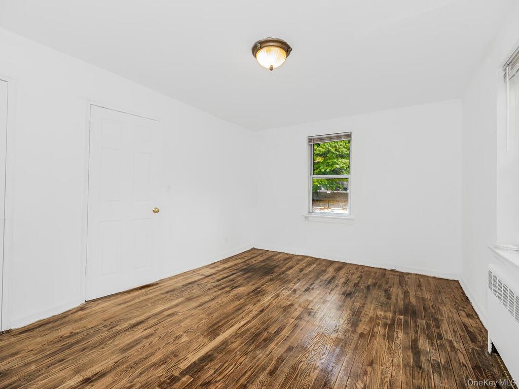 144 Ravine Avenue, Unit 2C Yonkers, NY 10701 - Photo 4 of 15 Unfurnished room with dark hardwood / wood-style floors and radiator heating unit