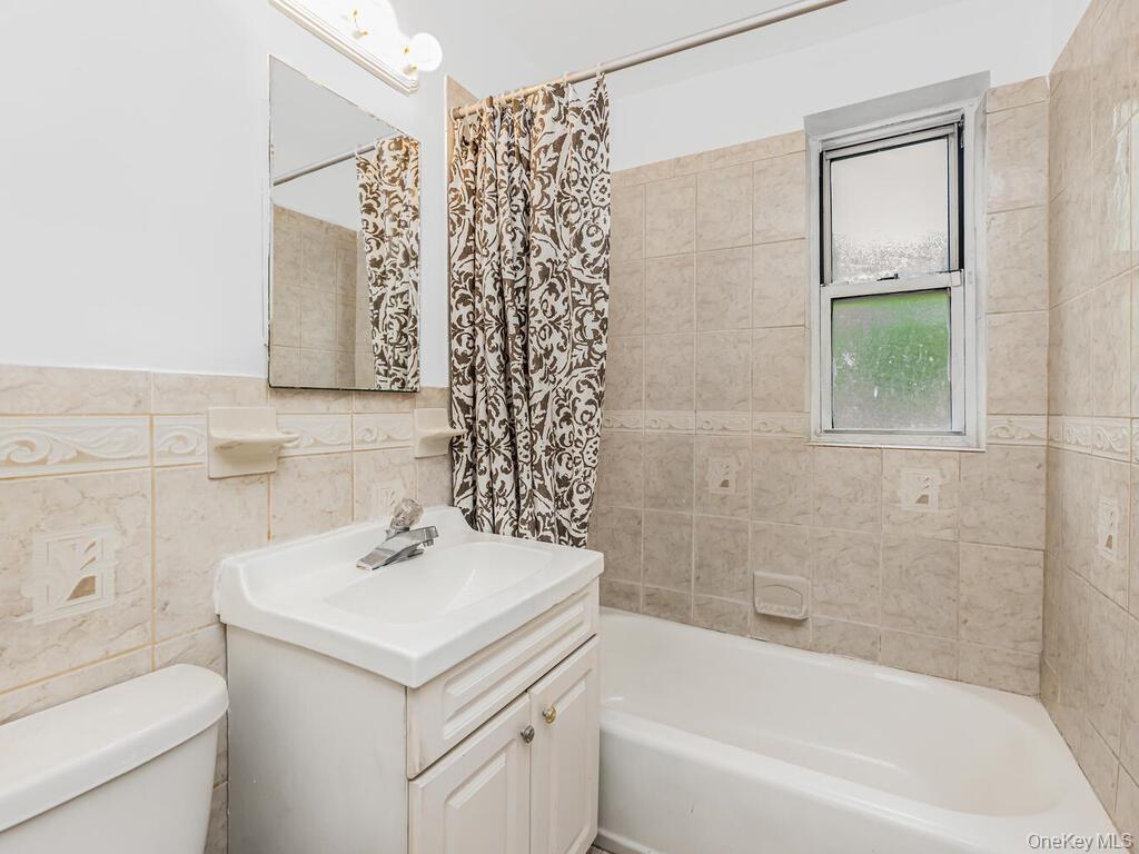 144 Ravine Avenue, Unit 2C Yonkers, NY 10701 - Photo 5 of 15 Full bathroom with vanity, tile walls, shower / tub combo, and toilet