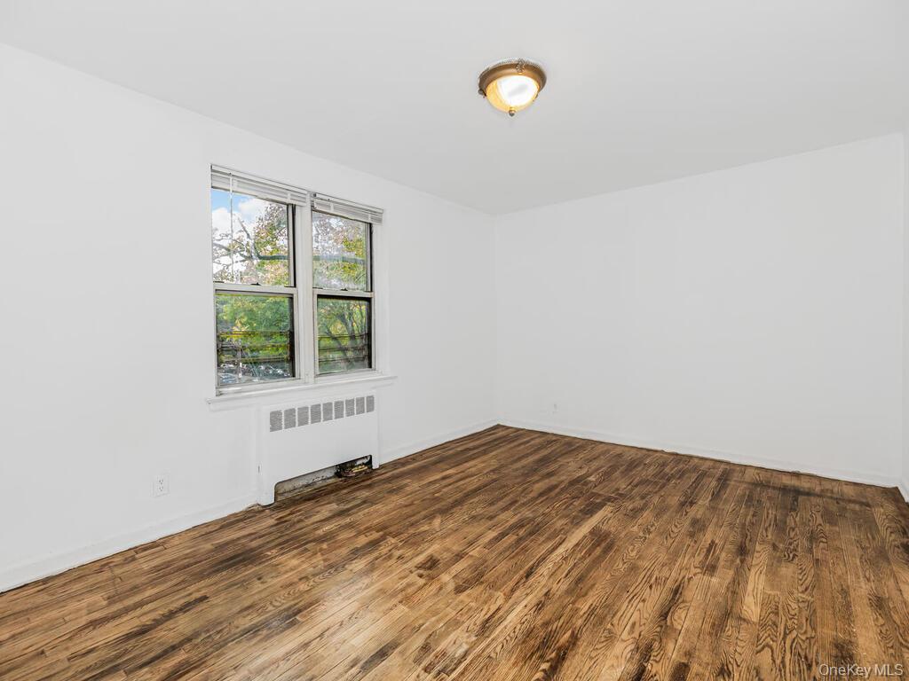 144 Ravine Avenue, Unit 2C Yonkers, NY 10701 - Photo 7 of 15 Unfurnished room with dark hardwood / wood-style floors and radiator heating unit