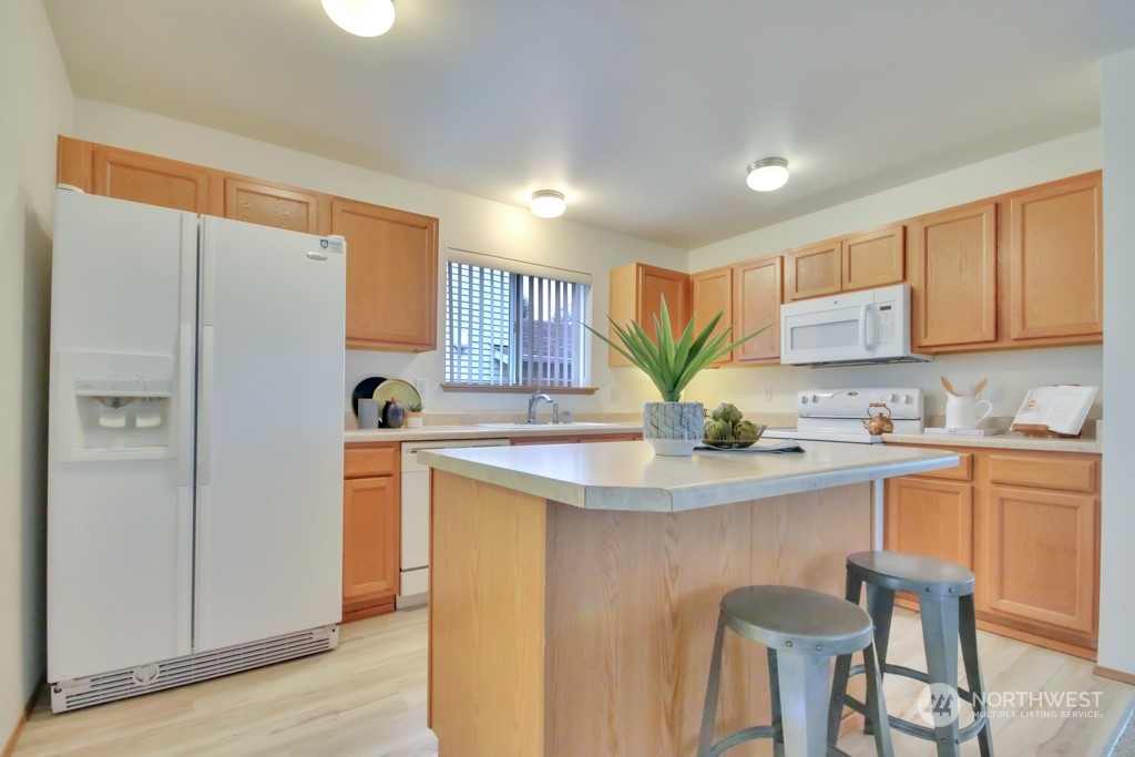 4010 East R Street Tacoma, WA 98404 - Photo 11 of 28 a kitchen with stainless steel appliances granite countertop a refrigerator a sink a stove a dining table and chairs with wooden floor