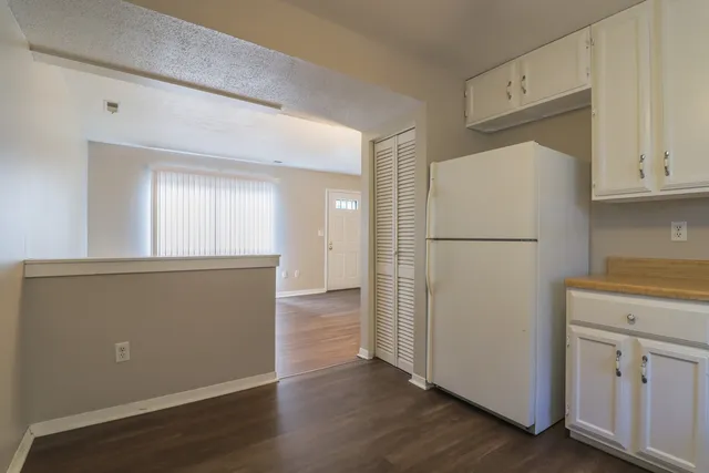 a view of a kitchen with refrigerator and wooden floor