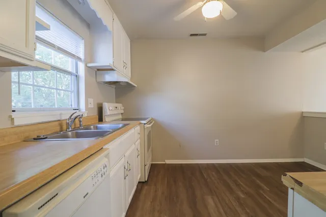 a kitchen with a sink dishwasher and stove with wooden floor