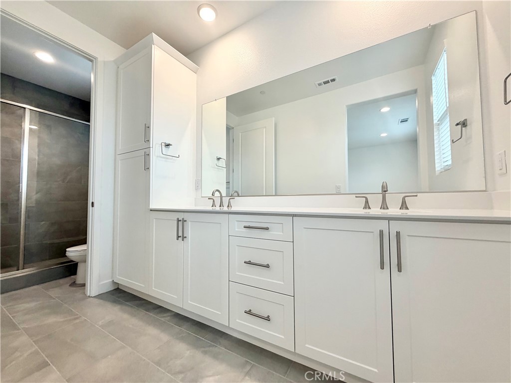 26893 Rubicon Road Menifee, CA 92586 - Photo 26 of 32 a bathroom with a shower sink and mirror