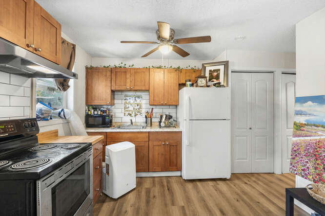 75-164 Lunapule Road Kailua-Kona, HI 96740 - Photo 7 of 27 a kitchen with granite countertop a refrigerator a stove a sink dishwasher and white cabinets with wooden floor