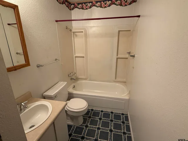 a bathroom with a granite countertop sink toilet a mirror and bathtub