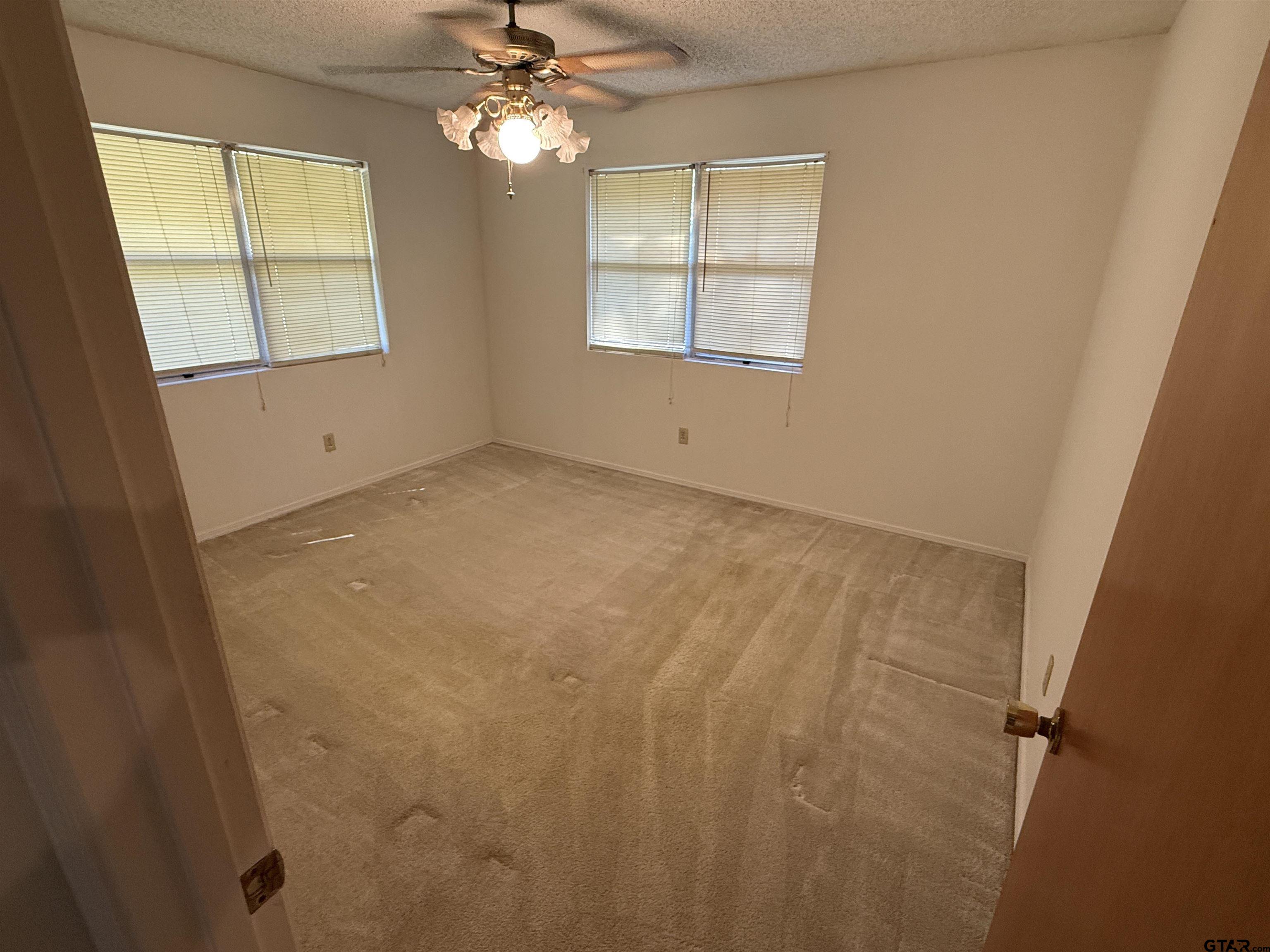 226 Caroline Street Rusk, TX 75785 - Photo 17 of 21 en empty room with windows and chandelier fan