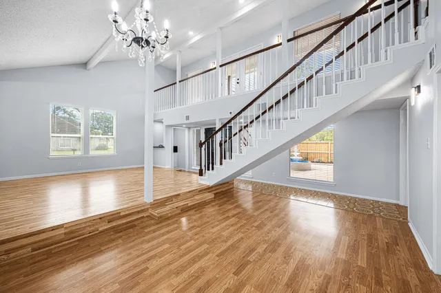 a view of an empty room with window and wooden floor