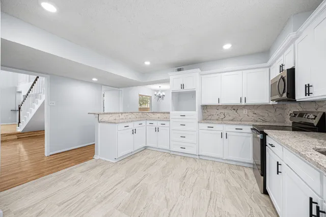 a kitchen with granite countertop white cabinets and white appliances
