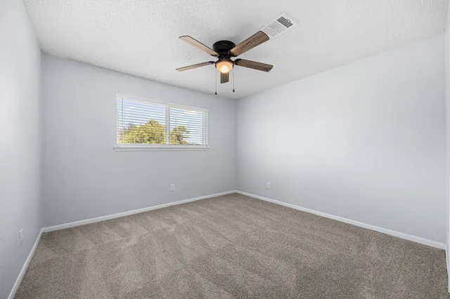 a view of empty room with windows and ceiling fan