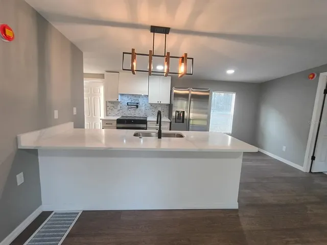a kitchen with a sink a refrigerator and chandelier