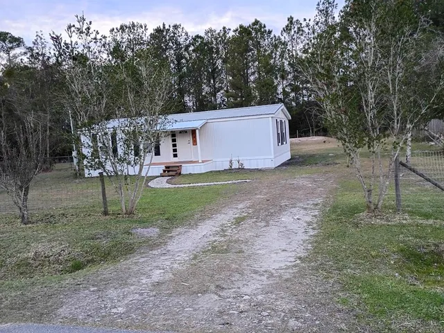 a view of a house with a yard and large trees