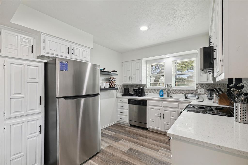 1813 Cross Bend Road Plano, TX 75023 - Photo 20 of 30 a kitchen with a refrigerator a sink a stove and white cabinets