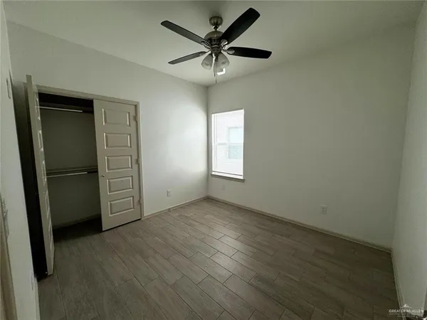 an empty room with a window and a ceiling fan