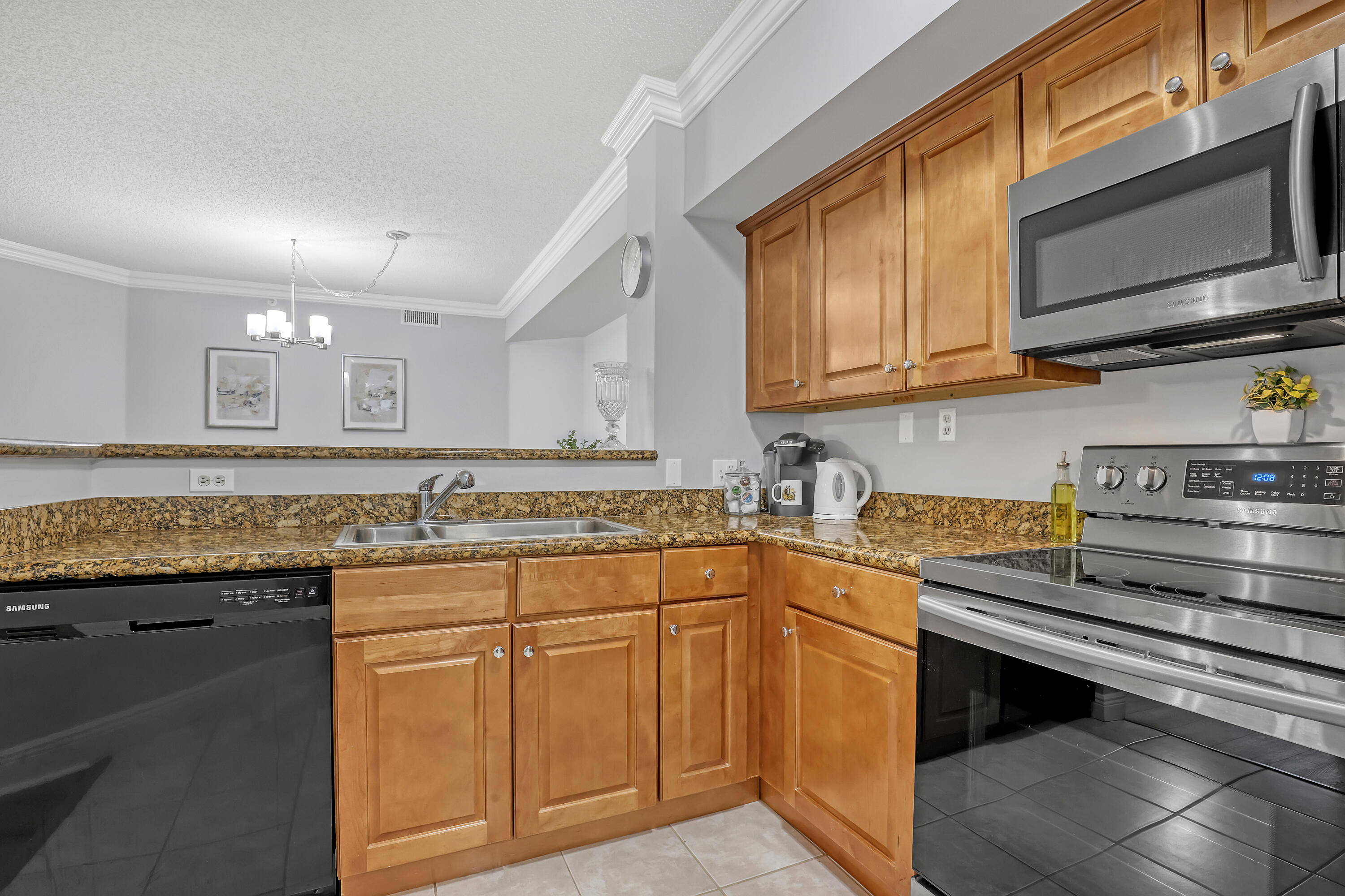 11790 St Andrews Place, Unit 105 Wellington, FL 33414 - Photo 12 of 55 a kitchen with stainless steel appliances granite countertop a stove a sink and a microwave