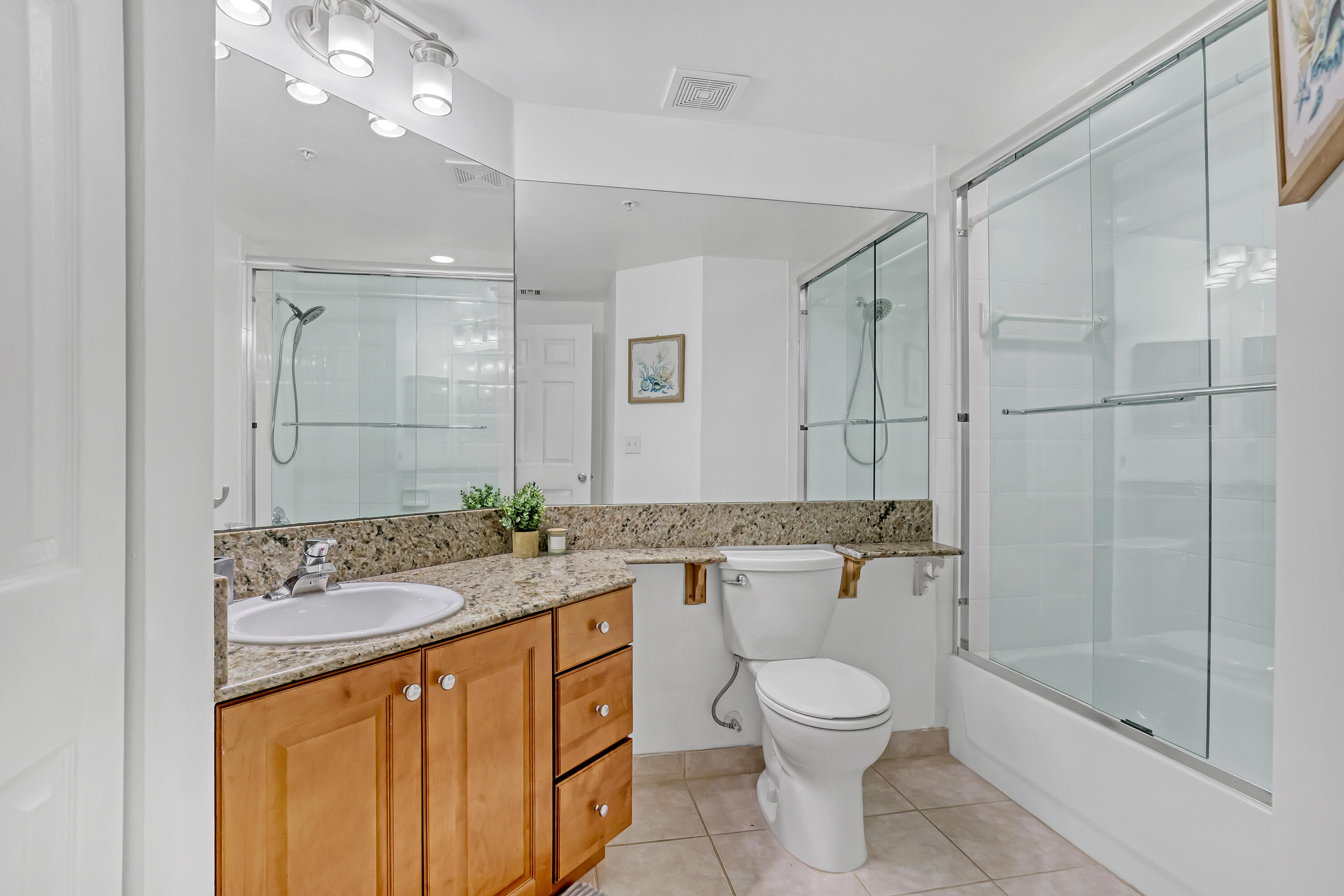 11790 St Andrews Place, Unit 105 Wellington, FL 33414 - Photo 26 of 55 a bathroom with a granite countertop sink a toilet a mirror and shower