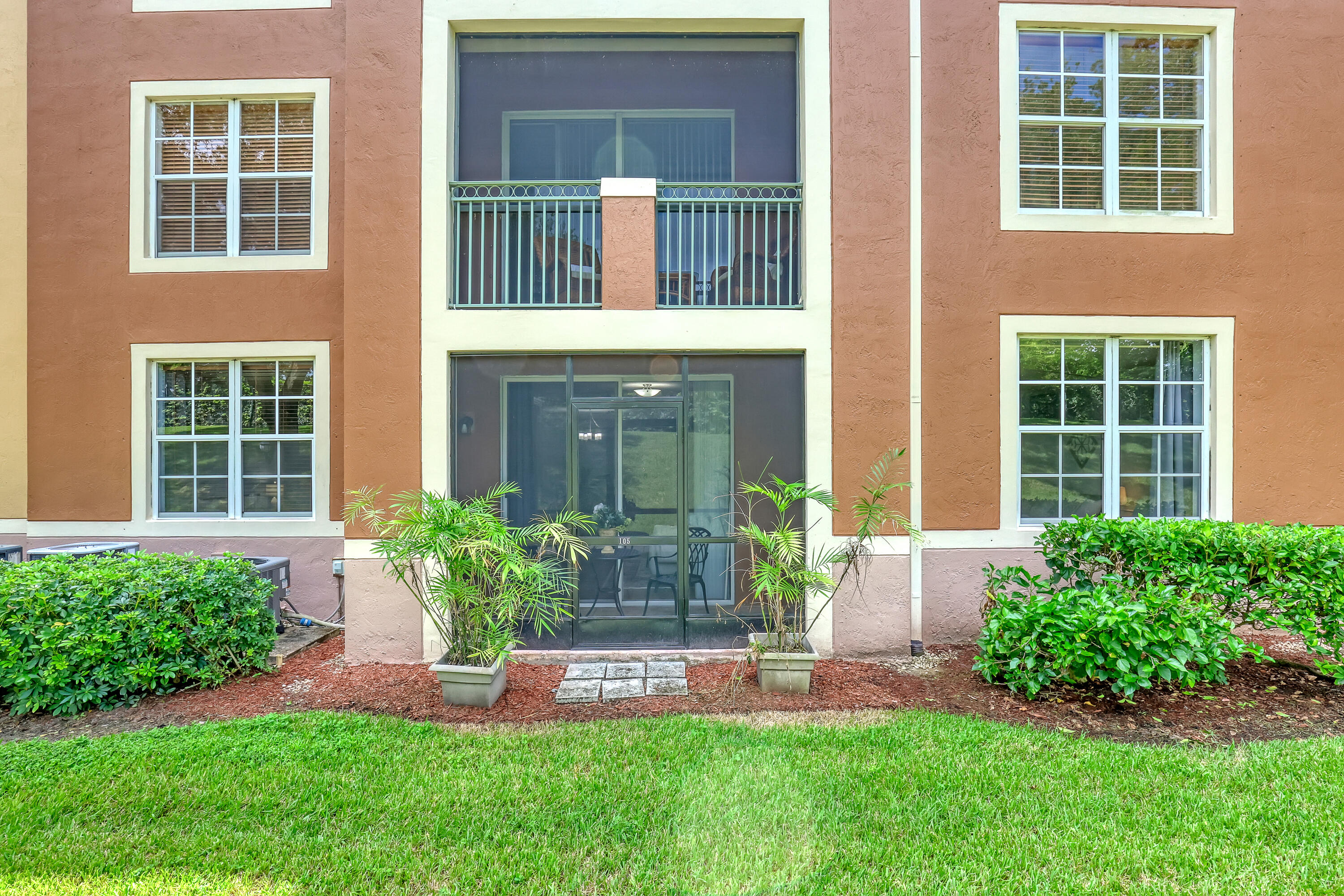 11790 St Andrews Place, Unit 105 Wellington, FL 33414 - Photo 32 of 55 a front view of a house with a yard and potted plants