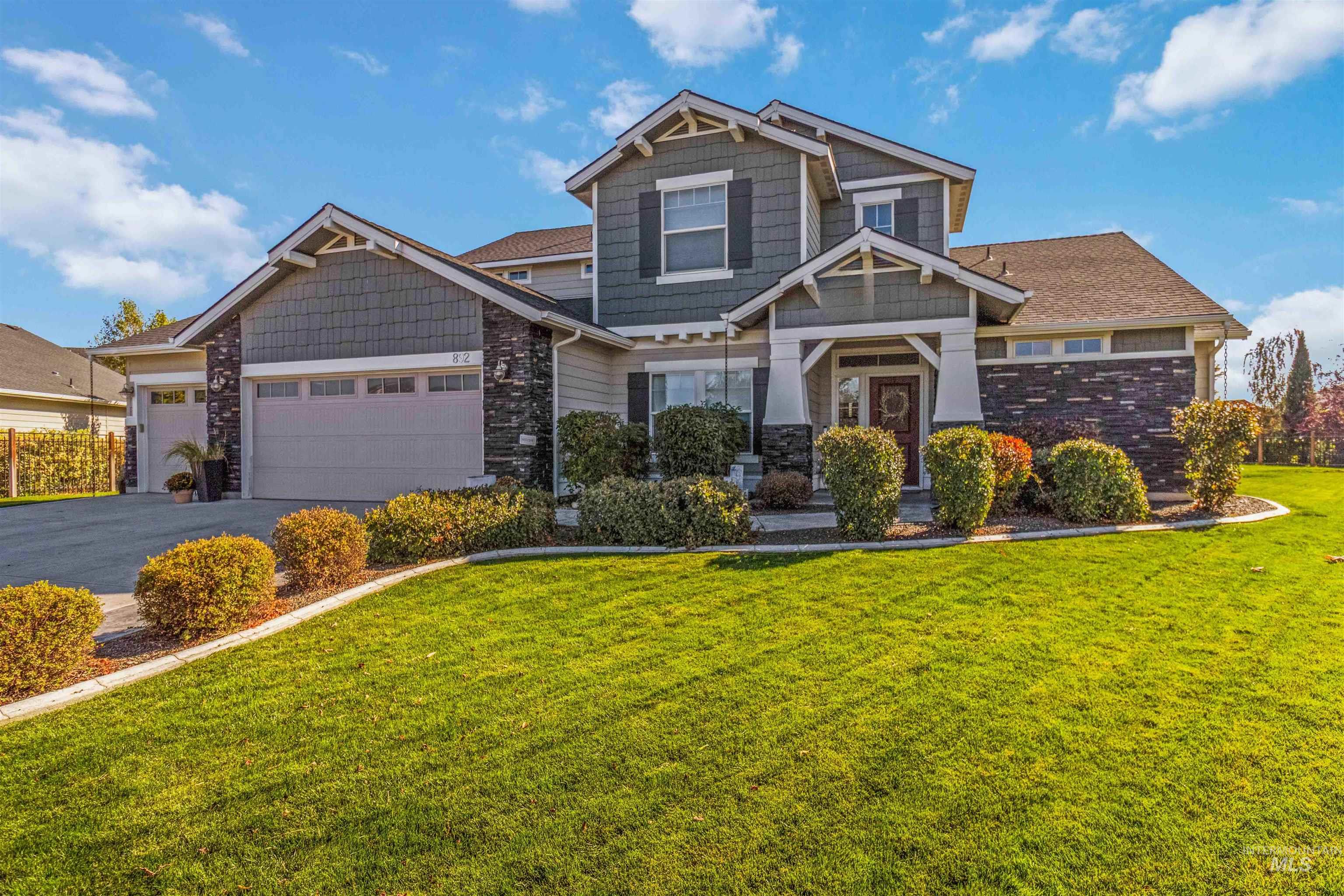 Craftsman-style home with a front yard, asphalt driveway, a garage, and stone siding