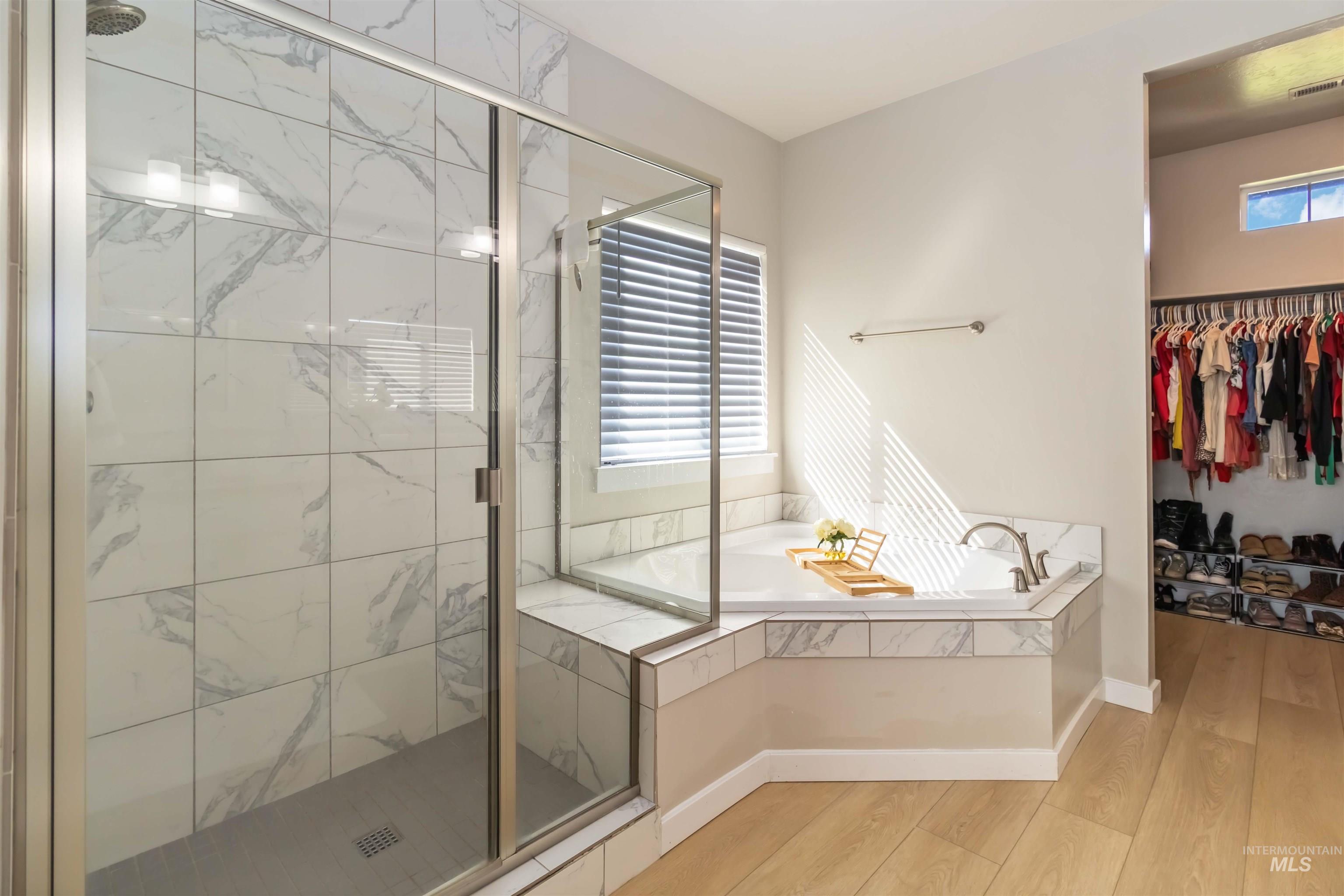 892 North Chastain Lane Eagle, ID 83616 - Photo 21 of 45 Full bath featuring a marble finish shower, a garden tub, a spacious closet, and light wood-style floors