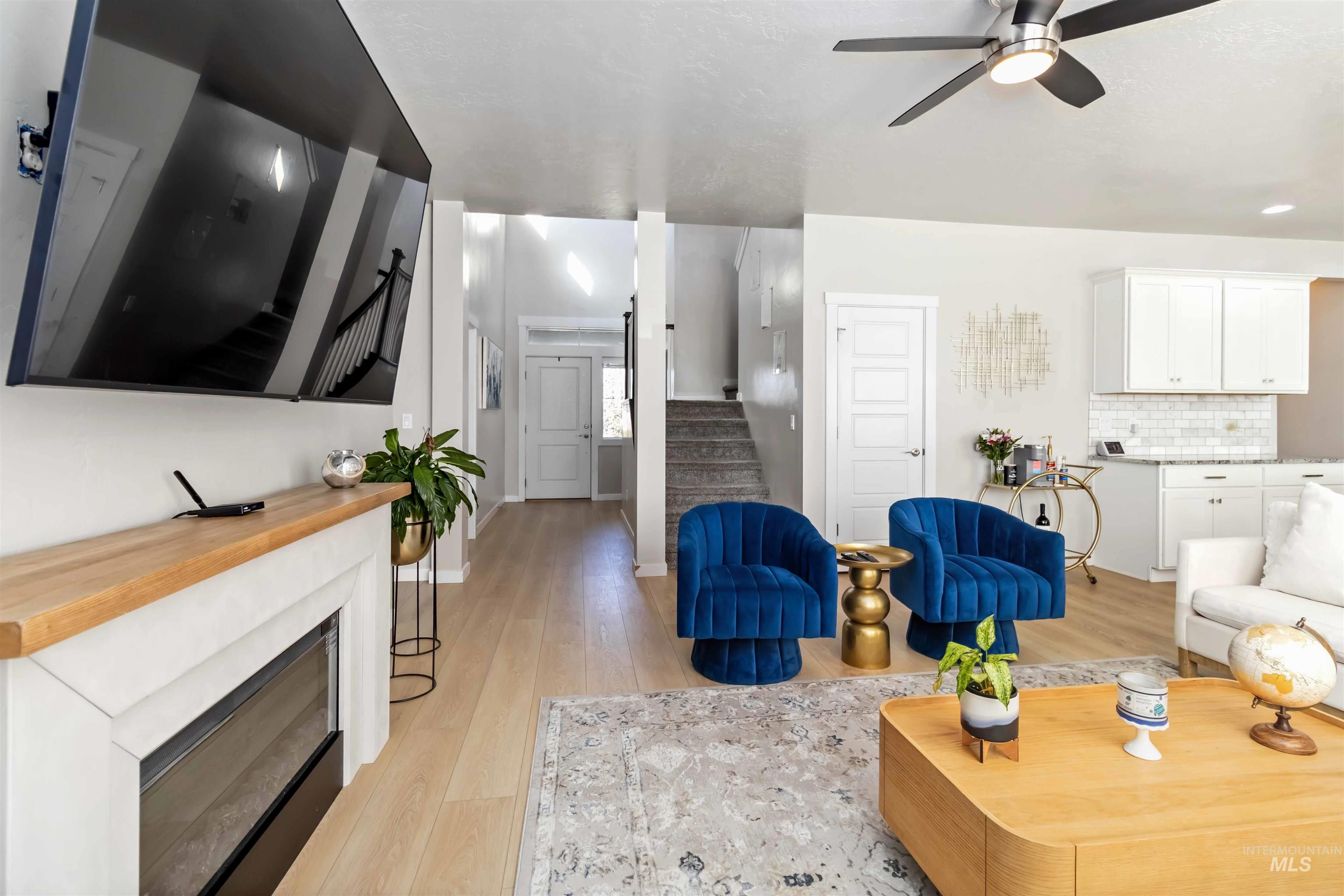 892 North Chastain Lane Eagle, ID 83616 - Photo 4 of 45 Living area featuring stairs, light wood finished floors, a fireplace, and ceiling fan