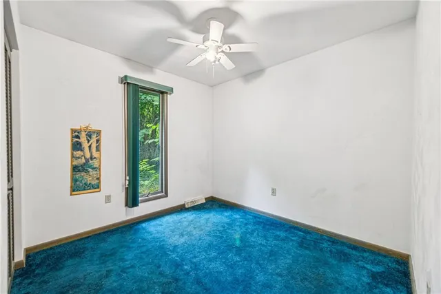 an empty room with windows and ceiling fan