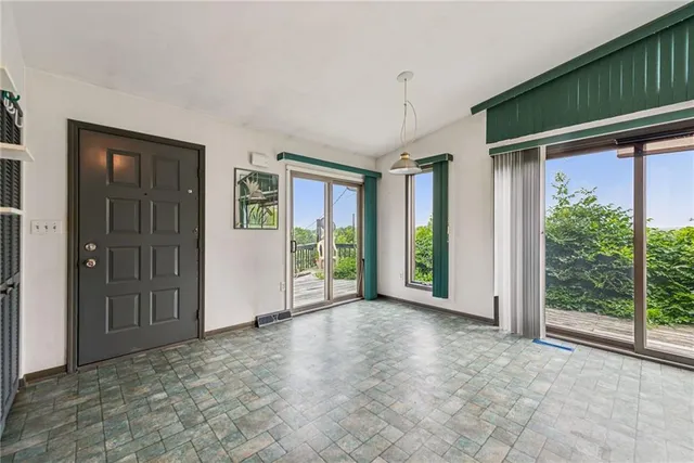 a view of an empty room with glass door and windows