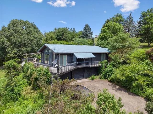 an aerial view of a house with balcony and trees all around