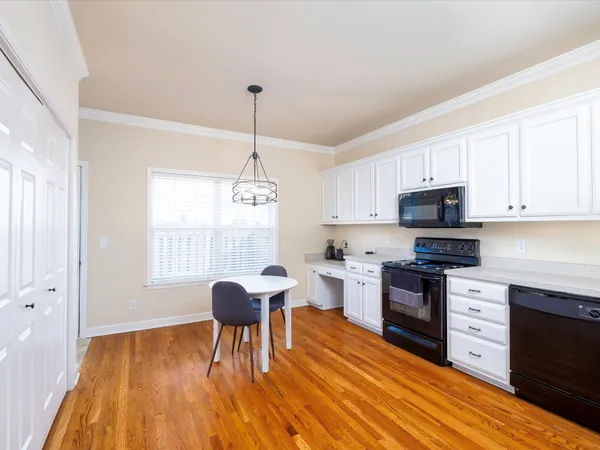 a kitchen with stainless steel appliances granite countertop a stove top oven a sink dishwasher and a dining table with wooden floor
