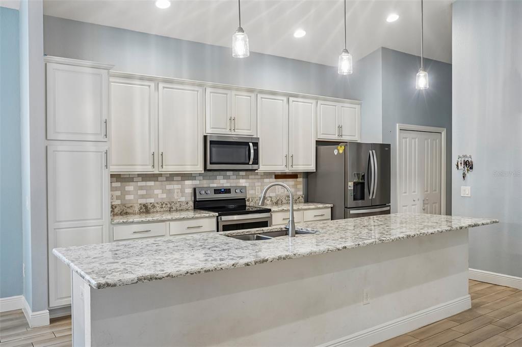10339 Addison Shore Way Oxford, FL 34484 - Photo 37 of 54 a kitchen with stainless steel appliances granite countertop a sink refrigerator and microwave