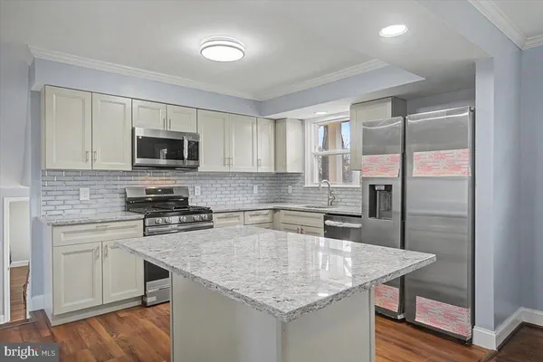 a kitchen with stainless steel appliances granite countertop a sink a stove and microwave