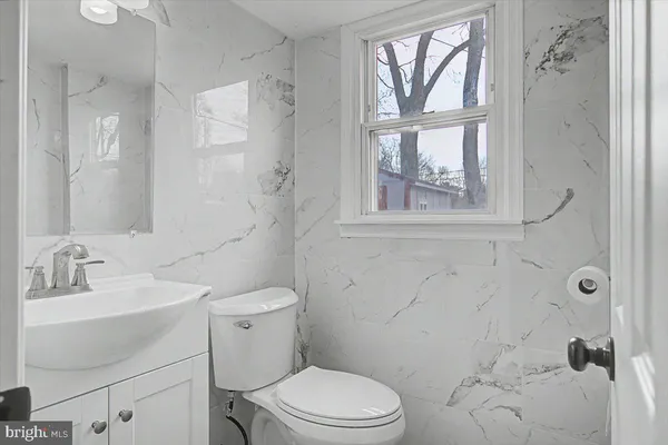 a bathroom with a toilet sink vanity and windows