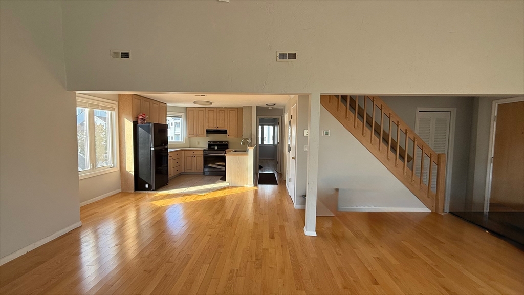 114 Burkhall Street, Unit R Weymouth, MA 02190 - Photo 3 of 15 a view of an empty room with wooden floor and a kitchen