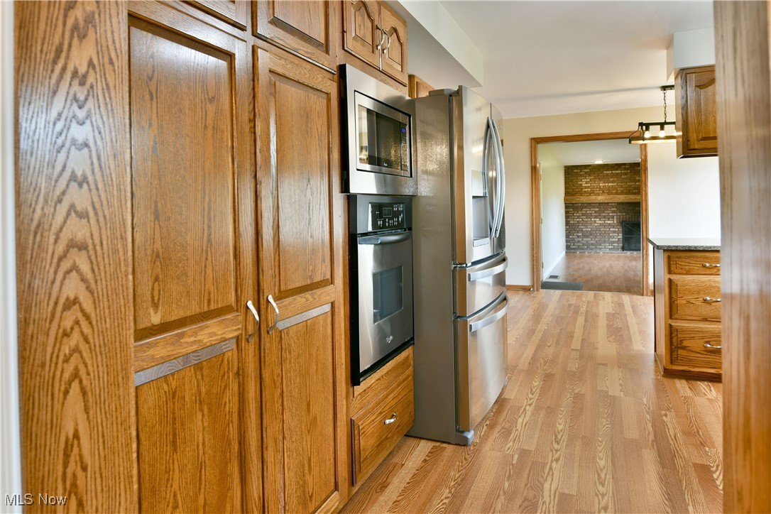 2153 Stillwagon Road Southeast Warren, OH 44484 - Photo 13 of 50 Kitchen with stainless steel appliances, brown cabinets, light wood-type flooring, and baseboards