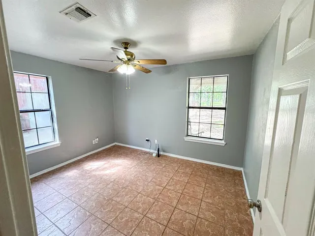an empty room with windows and fan