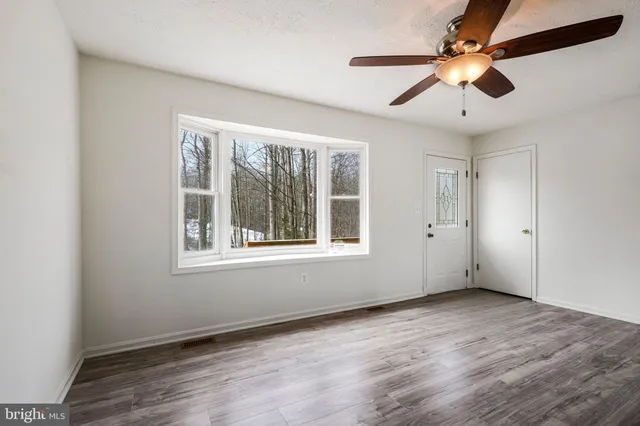 a view of an empty room with wooden floor and a window