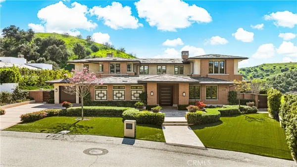 a front view of a house with a garden and trees