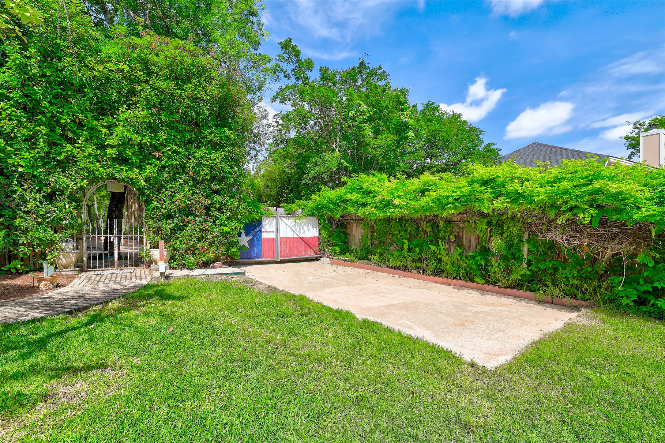 110 South Ridge Circle Georgetown, TX 78628 - Photo 37 of 37 Landscaped exterior featuring a gated entry arch, a concrete drive, a privacy fence with lush greenery, and a manicured lawn