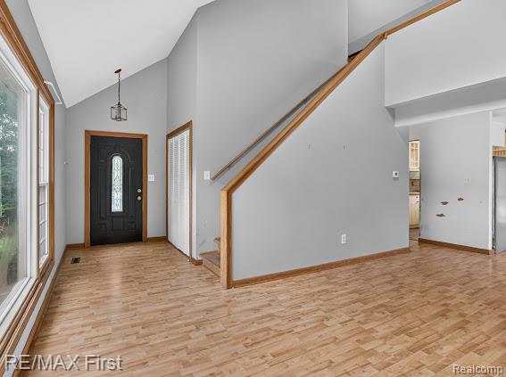56375 Bates Road New Baltimore, MI 48051 - Photo 14 of 35 Vaulted ceiling, wood-finish flooring, staircase with wood railing, dark paneled front door with decorative glass, and a built-in closet with bi-fold doors