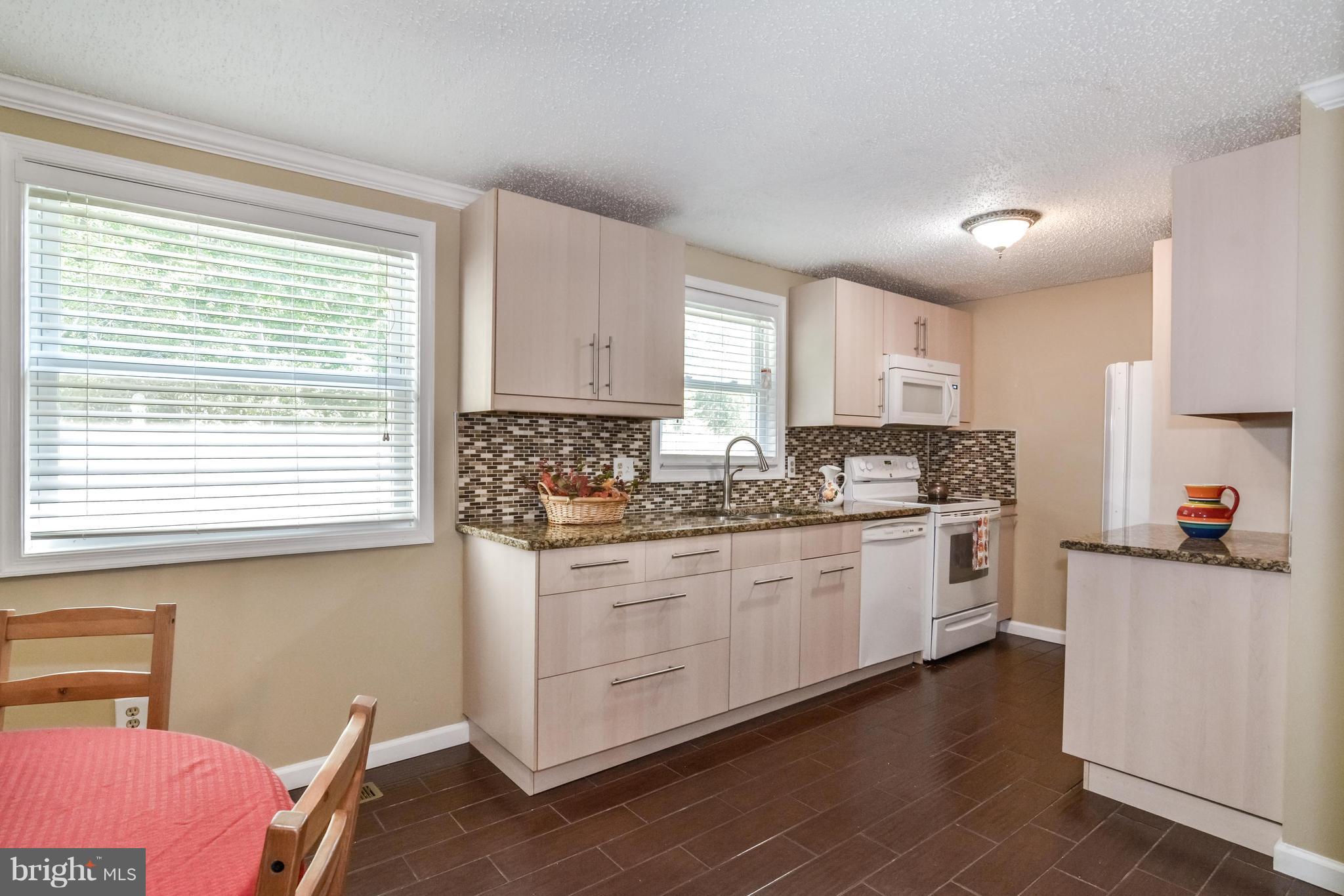 8609 Spring Creek Court Springfield, VA 22153 - Photo 30 of 30 a kitchen with granite countertop wooden cabinets a stove a sink and a window