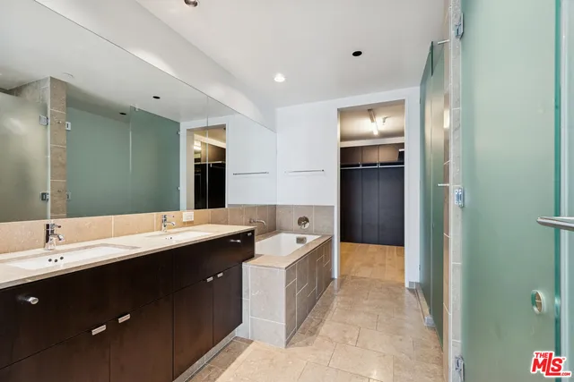 a spacious bathroom with a double vanity sink a large mirror and a shower