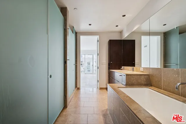 a bathroom with a tub a sink and a large mirror