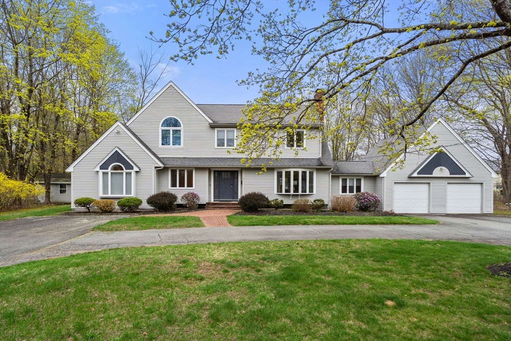 a view of house with a big yard and large trees