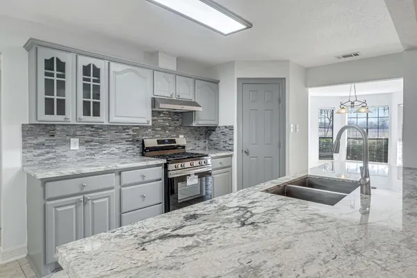 a kitchen with stainless steel appliances kitchen island granite countertop a stove sink and cabinets