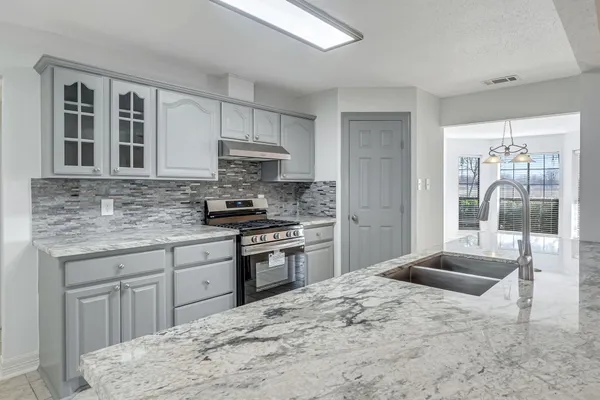 a kitchen with stainless steel appliances kitchen island granite countertop a stove sink and cabinets