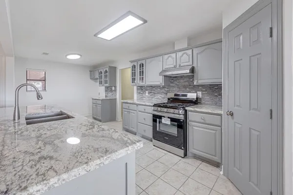 a kitchen with kitchen island granite countertop a sink stove and refrigerator