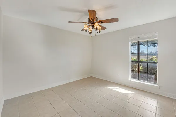 an empty room with windows and fan
