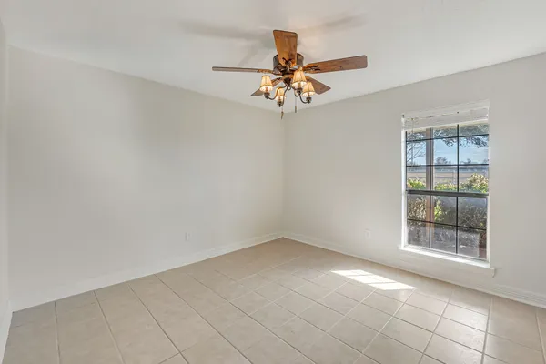 an empty room with windows and fan